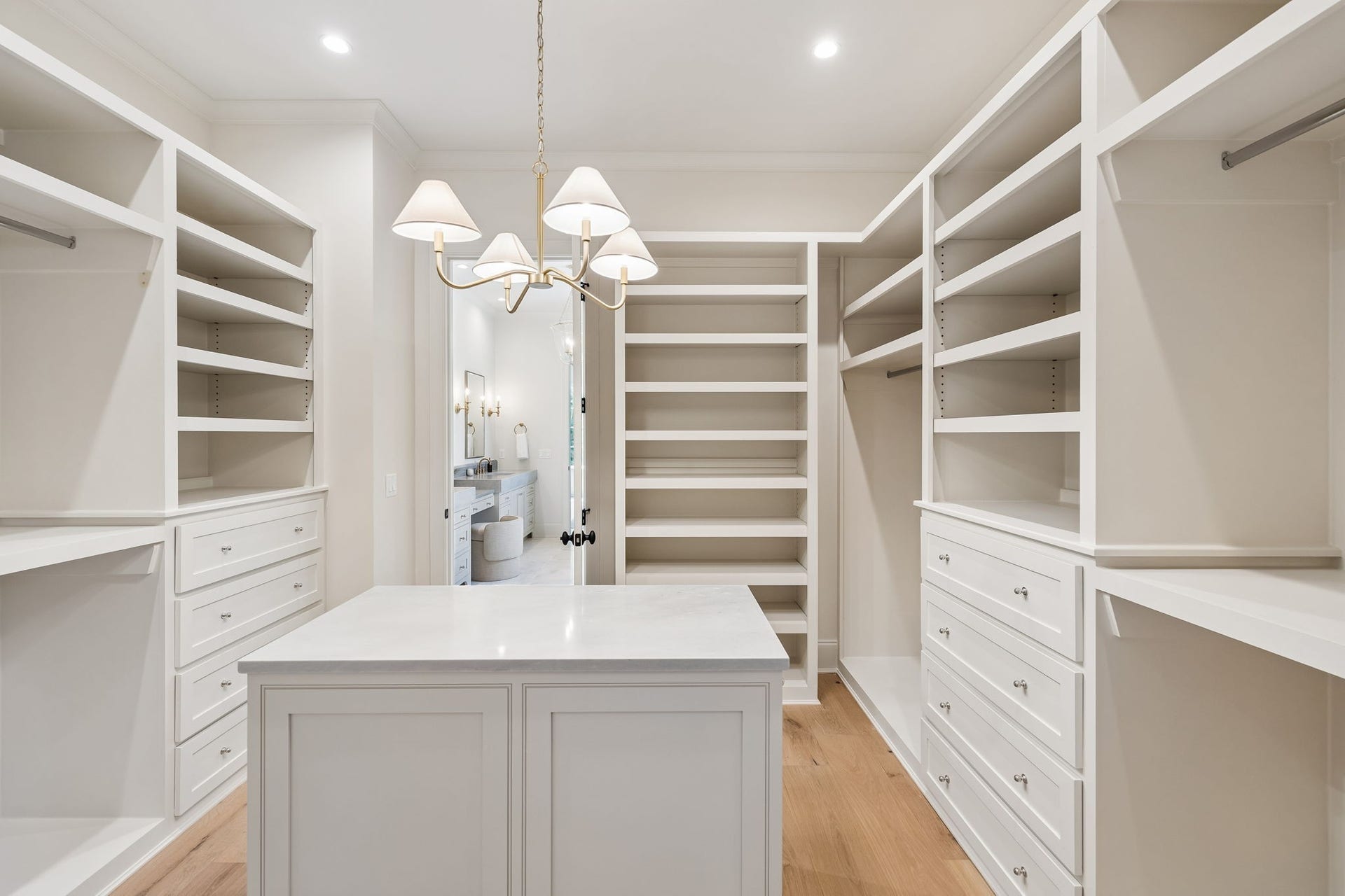 1133 Maplehurst Ln, Nashville, TN 37204 Oversized primary walk-in closet features extensive custom built-ins, abundant drawer and hanging space, and a large center island for additional storage. Direct access to the main-level laundry room adds exceptional everyday convenience.
