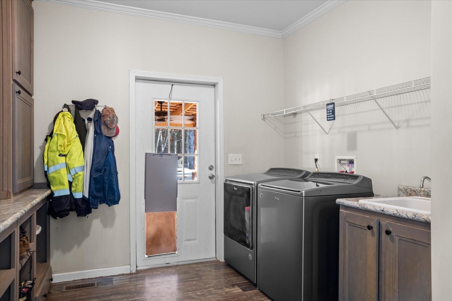 Laundry room has a doggie door to the back deck, a sink and extra storage