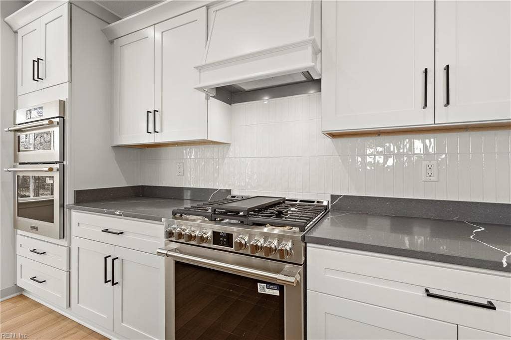 Eat in Kitchen. The Eat in Kitchen offers a center island with overhang for additional seating, pendant & recessed lighting, large dining area with chandelier, apron sink and goose neck faucet, soft close custom cabinets, quartz counters, ceramic tile backsplash, & walk in pantry w/ wood shelving.