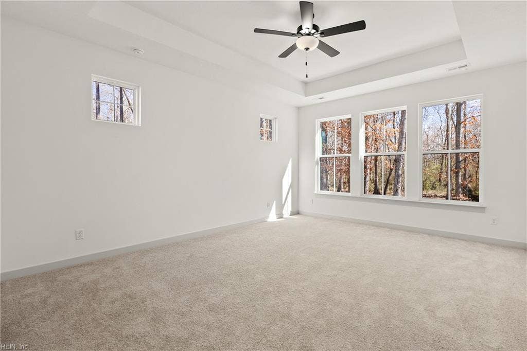 1st Floor Owner's Suite.The 1st Floor Owner's Suite offers a tray ceiling, ceiling fan with light, carpeting, ensuite bath, and large walk in closet with wood shelving.