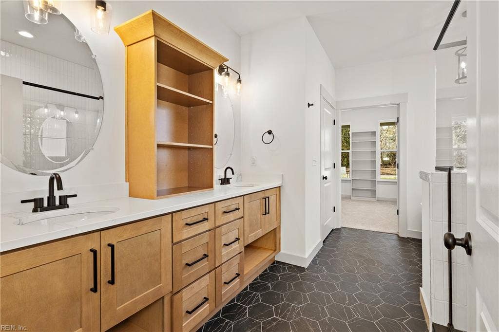 1st Floor Owner's Suite full bath includes custom soft close cabinets and drawers, double bowl vanity, ceramic tile flooring, stand alone soaking tub, step in shower with tile surround, and water closet.