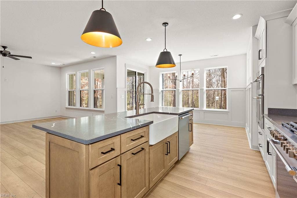 Eat in Kitchen. The Eat in Kitchen offers a center island with overhang for additional seating, pendant & recessed lighting, large dining area with chandelier, apron sink and goose neck faucet, soft close custom cabinets, quartz counters, ceramic tile backsplash, & walk in pantry w/ wood shelving.