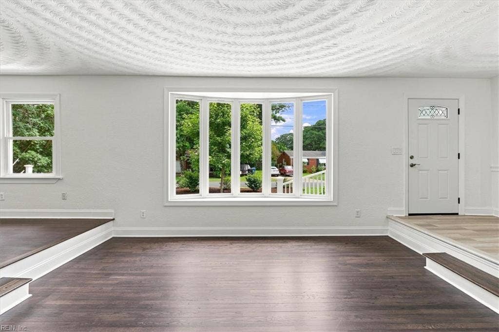 Step down formal living room with hardwood floors and bay window