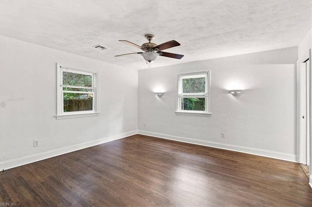 Spacious Primary with wall sconces and lighted ceiling fan.