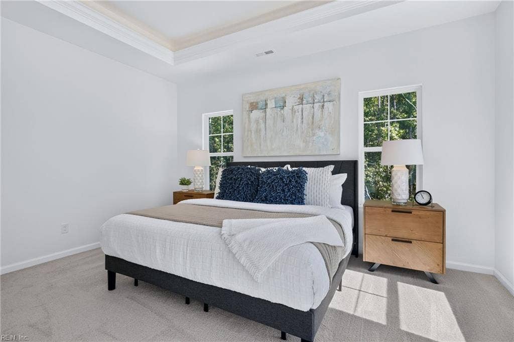 Second view of the primary bedroom flooded with natural light, a decorative ceiling,  walk-in closet and attached primary bathroom