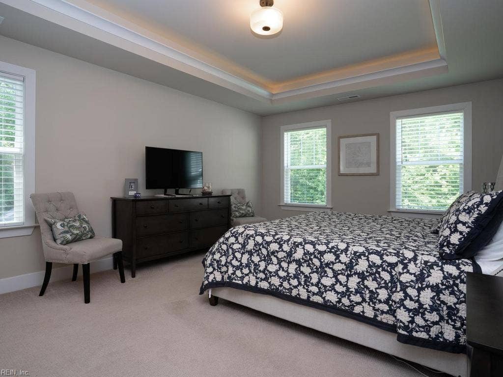 This primary suite serves as the ultimate owner's retreat, seamlessly blending architectural elegance with modern luxury to create a private, spa-like sanctuary. In the bedroom, a dramatic tray ceiling adds striking depth and volume, while concealed cove lighting casts a soft, warm glow