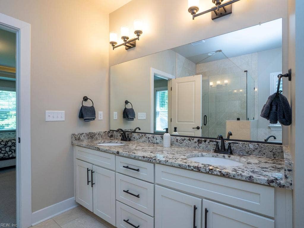 Step through the transition into the bathroom, where the atmosphere shifts into a peaceful, wellness-focused oasis. A deep under-mount soaking tub encased in custom stonework sits alongside a spacious walk-in shower , offering a rejuvenating escape from the daily grind