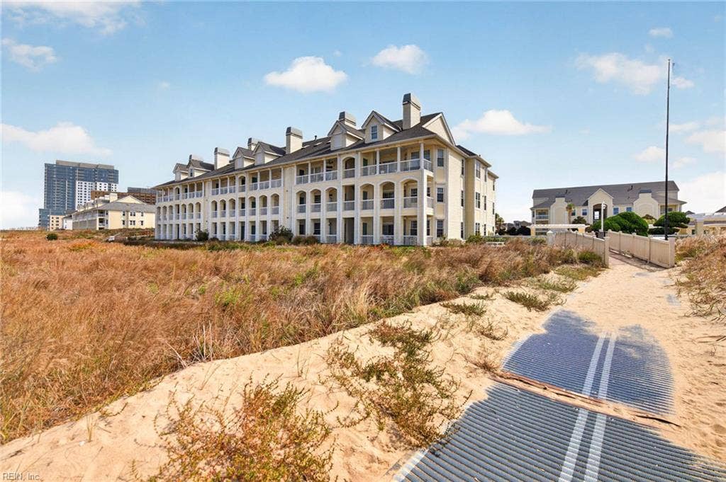 Lesner Pointe condominium building with arched covered porches beside the dune walkway to the Chesapeake Bay beach in Chic's Beach, Virginia Beach. Community amenities include the pool, beach access, and on-site grounds care. 23451.