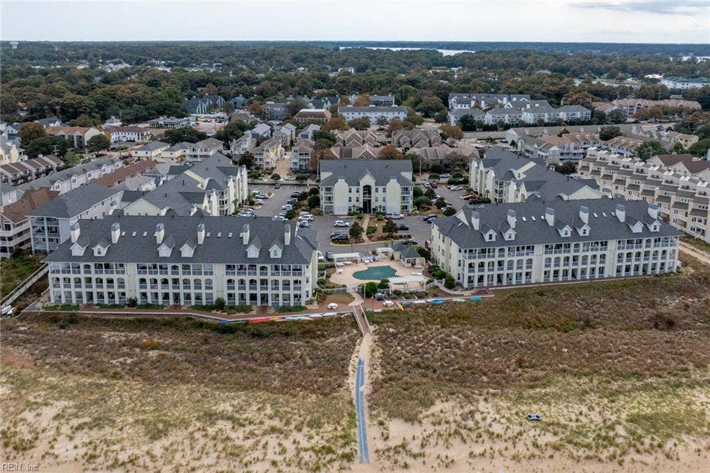 Aerial view of the Lesner Pointe community pool, boardwalk, and dune walkway leading to the Chesapeake Bay beach in Chic's Beach, Virginia Beach. Pool and beach access come with the community. Condo buildings surround the pool. 23451.