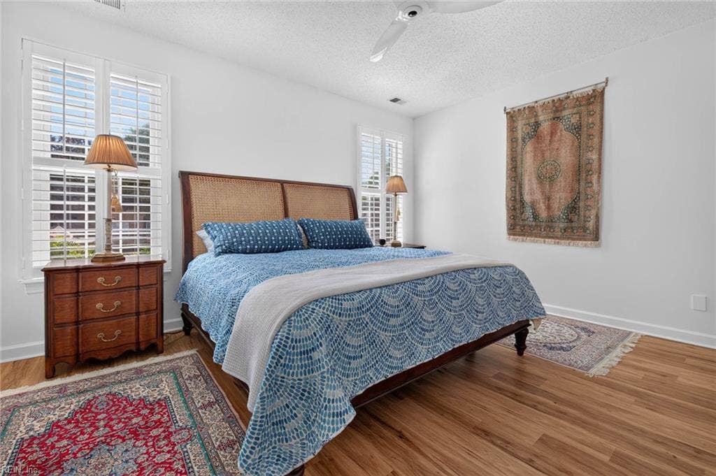 Primary bedroom with ceiling fan, two plantation-shuttered windows, and LVP flooring in this 3 bedroom, 2 bath first-floor condo at Lesner Pointe, Chic's Beach, Virginia Beach. Room fits a king-size bed with space for nightstands. 23451.