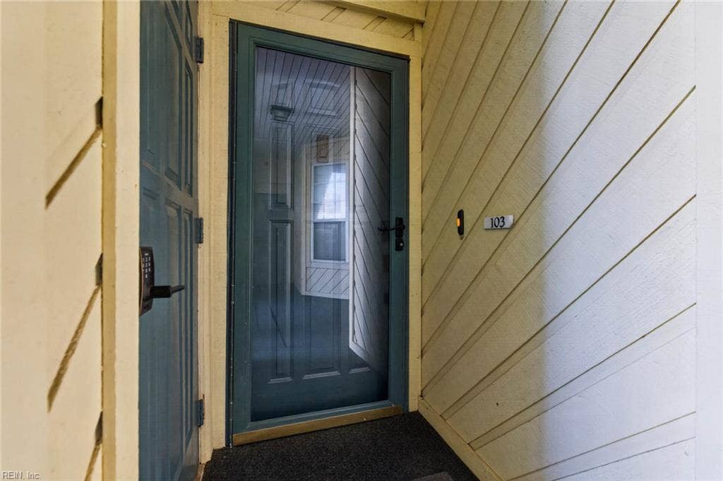 Entry to Unit 103 at 3159 Silver Sands Circle with keypad door lock, storm door, and covered ground-level landing in Lesner Pointe, Chic's Beach, Virginia Beach. First-floor 3 bedroom, 2 bath condo. 23451.