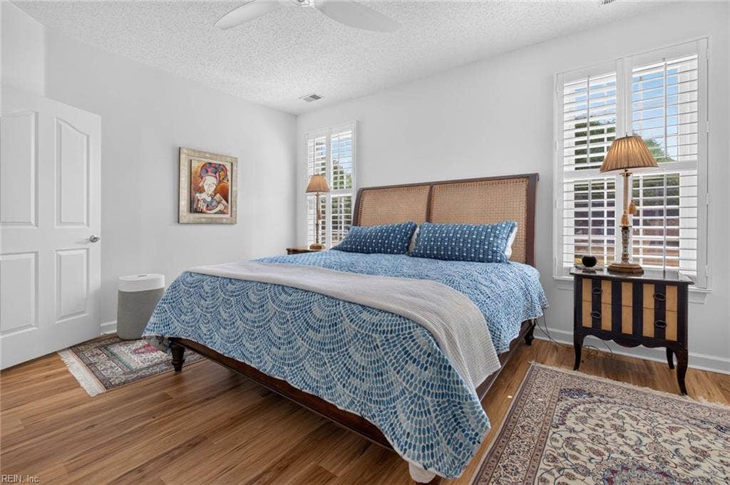 Primary bedroom with plantation shutters, ceiling fan, and LVP flooring in this 3 bedroom, 2 bath condo at Lesner Pointe, Virginia Beach. Two windows bring in natural light. First-floor unit with community pool and beach access in Chic's Beach.