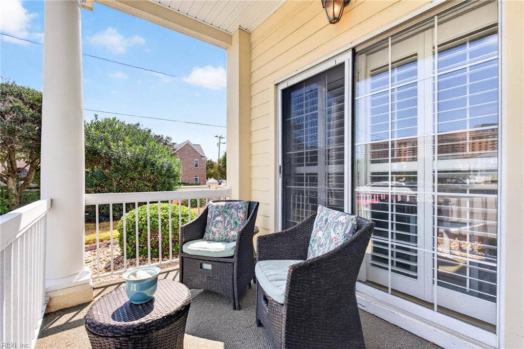 Covered patio with sliding glass door access, plantation shutters, and garden views at this first-floor Lesner Pointe condo in Chic's Beach, Virginia Beach. Ground-level location with the community pool and beach nearby. 23451.
