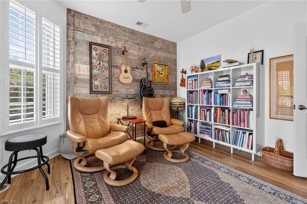 Den with reclaimed wood accent wall, plantation-shuttered corner window, ceiling fan, and LVP flooring. Flexible room works as a third bedroom, home office, or workout room in this Lesner Pointe condo, Chic's Beach, Virginia Beach. 23451.
