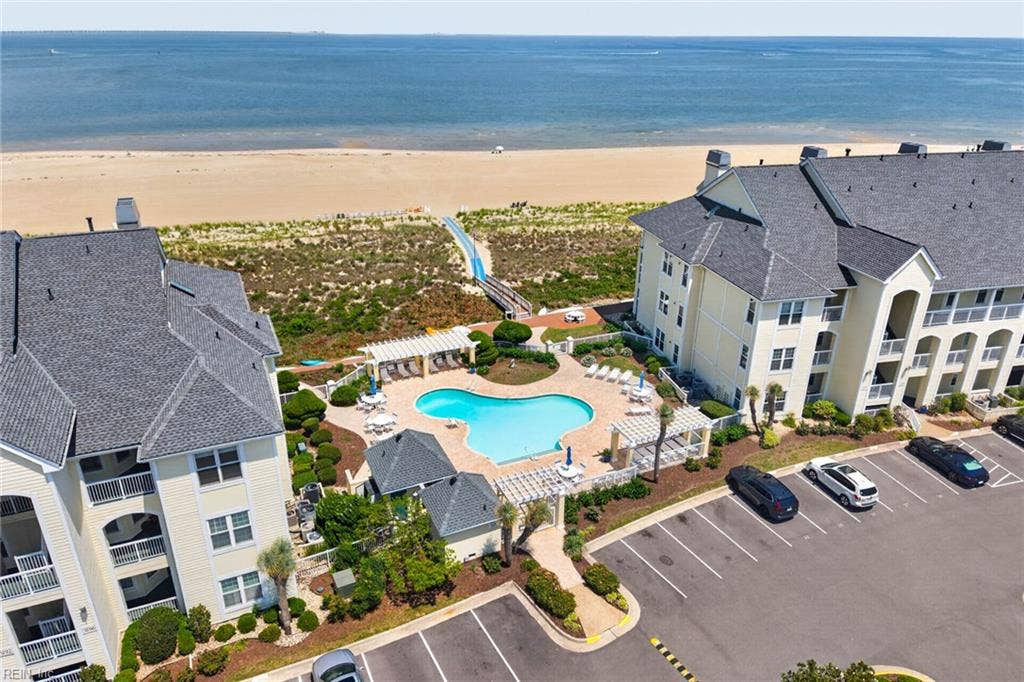 Community pool with two pergola lounge areas and a walkway to the Chesapeake Bay beach at Lesner Pointe in Chic's Beach, Virginia Beach. Pool and beach access come with the community. Parking lot sits beside the pool area. 23451.