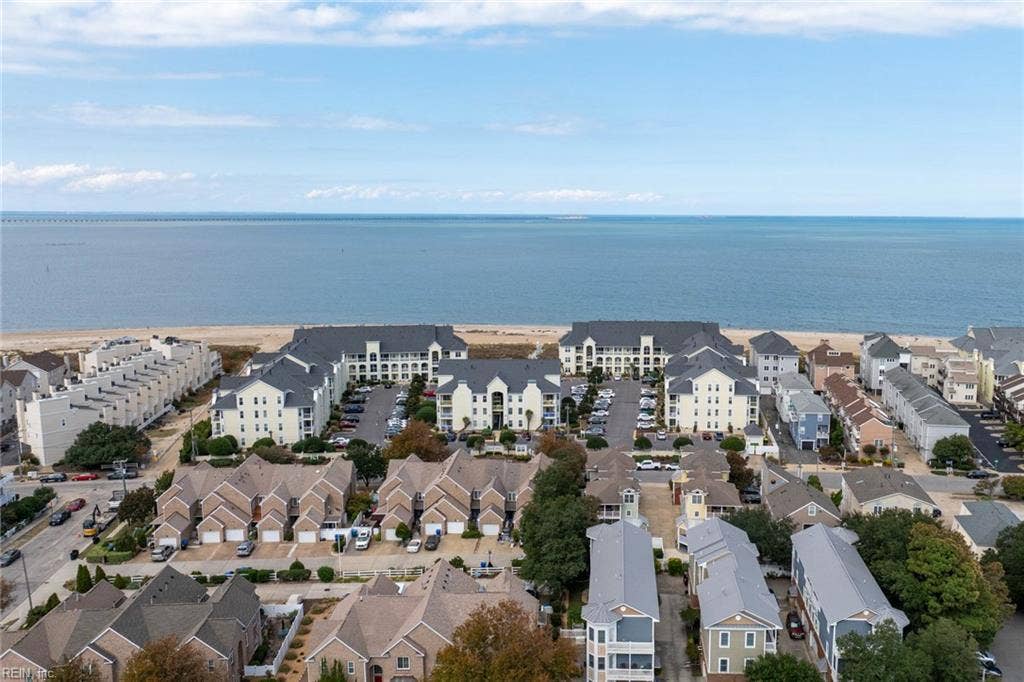 Aerial view of the Lesner Pointe condominium community on the Chesapeake Bay shoreline in Chic's Beach, Virginia Beach, with the Chesapeake Bay Bridge-Tunnel on the horizon. Parking, pool, and beach access are all part of the community. 23451.