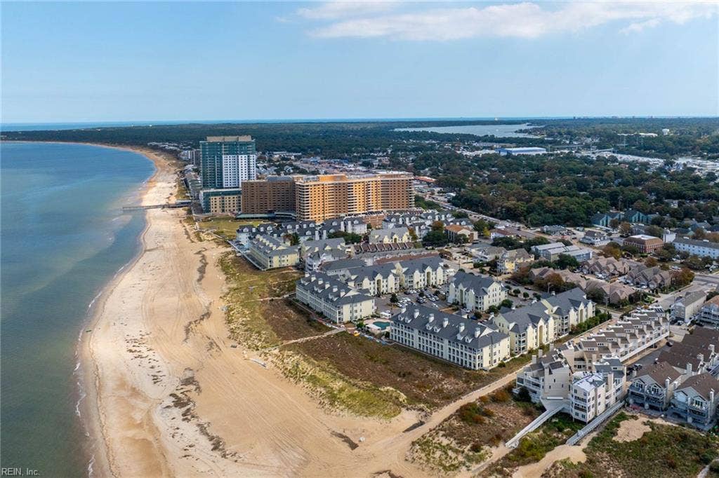 Aerial view of the Chesapeake Bay shoreline and the Lesner Pointe condominium community in Chic's Beach, Virginia Beach. Wide sandy beach and dune-lined shore run along the community. First-floor 3 bedroom condo offered in this setting.