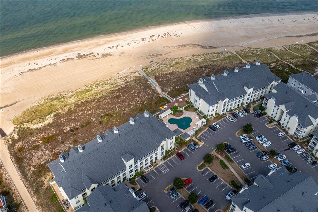 Aerial view of the Lesner Pointe community pool with pergolas and the Chesapeake Bay beach beyond the dunes in Chic's Beach, Virginia Beach. Pool and beach access come with this first-floor 3 bedroom condo. 23451.