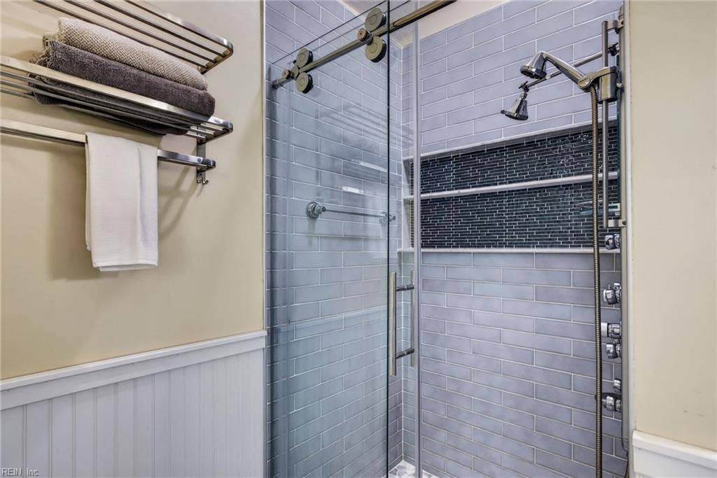 Primary bath features a beautifully updated shower alongside a freestanding tub.