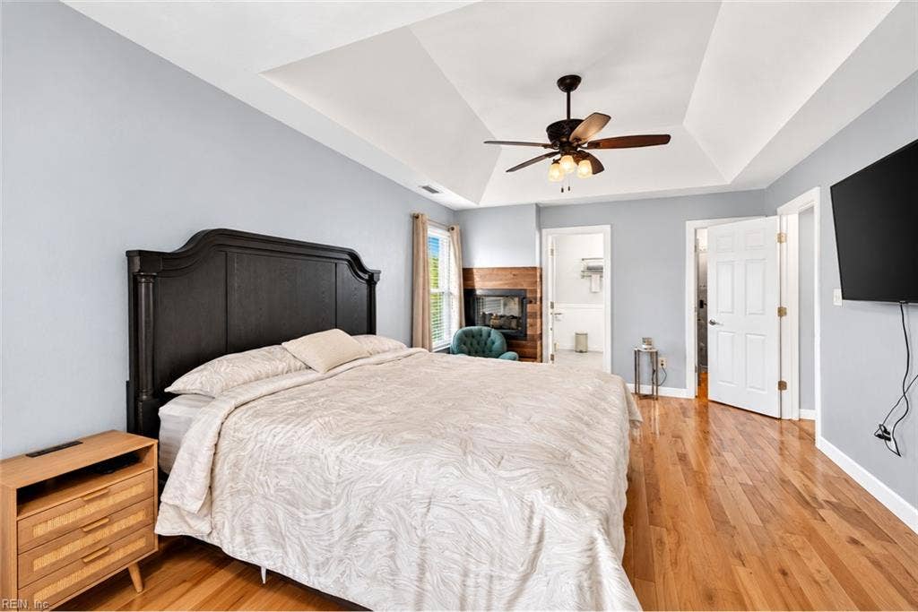 Generous primary suite with hardwood floors and tray ceiling