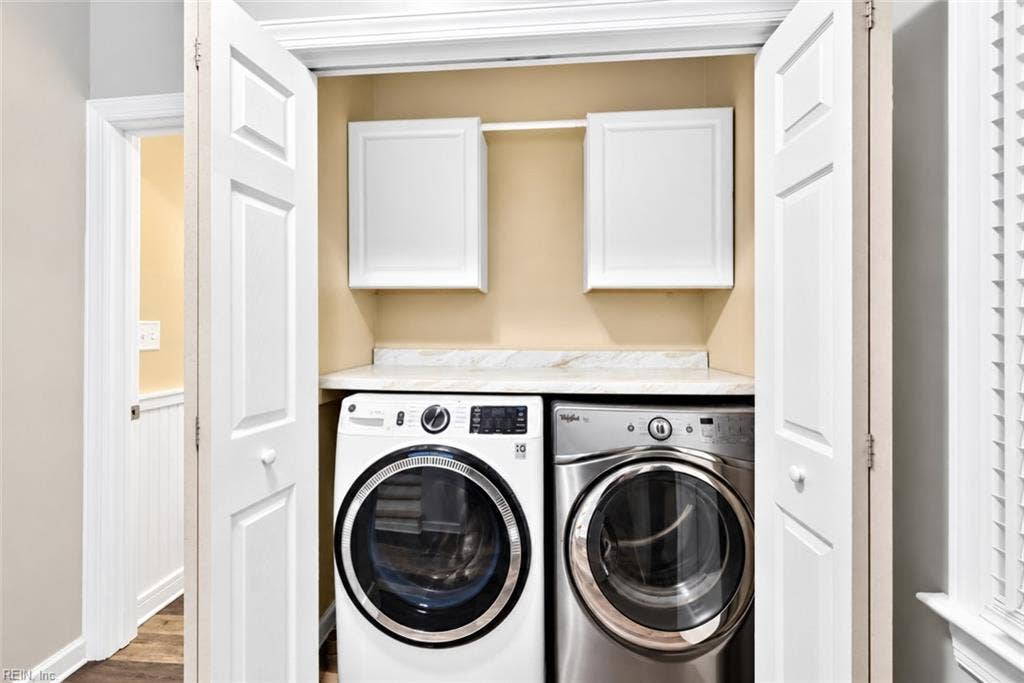 Convenient laundry area with upper cabinetry and countertop