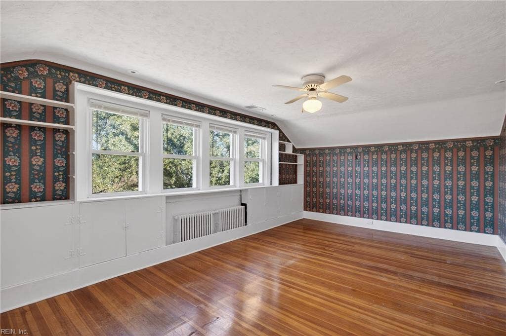 Primary bedroom with abundant natural light and original hardwood floor