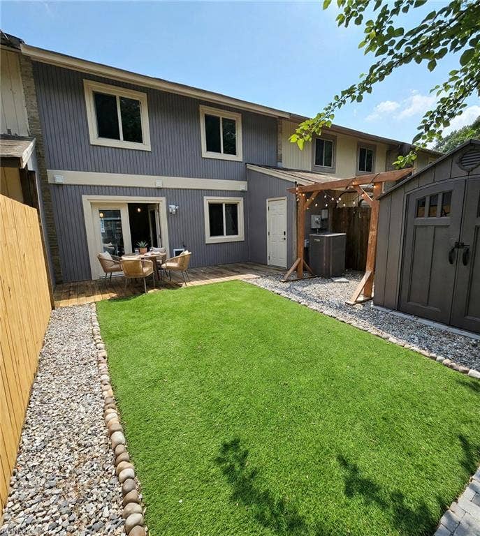 Fenced turf backyard with deck, pergola, and storage shed — no mowing! Virtually staged