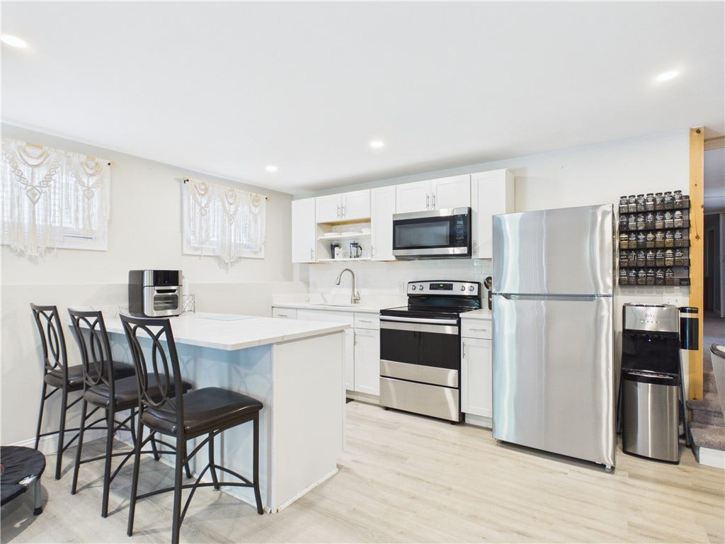 36 Bellevue Avenue, North Smithfield, RI 02896 Kitchenette within the lower-level in-law space, featuring white cabinetry, stainless steel appliances, and an island with seating.