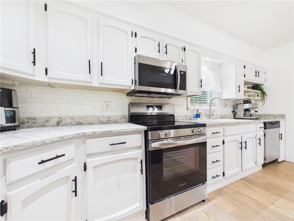 36 Bellevue Avenue, North Smithfield, RI 02896 Bright kitchen at 36 Bellevue Avenue featuring white cabinetry, stainless steel appliances, subway tile backsplash, granite countertops, and hardwood flooring.