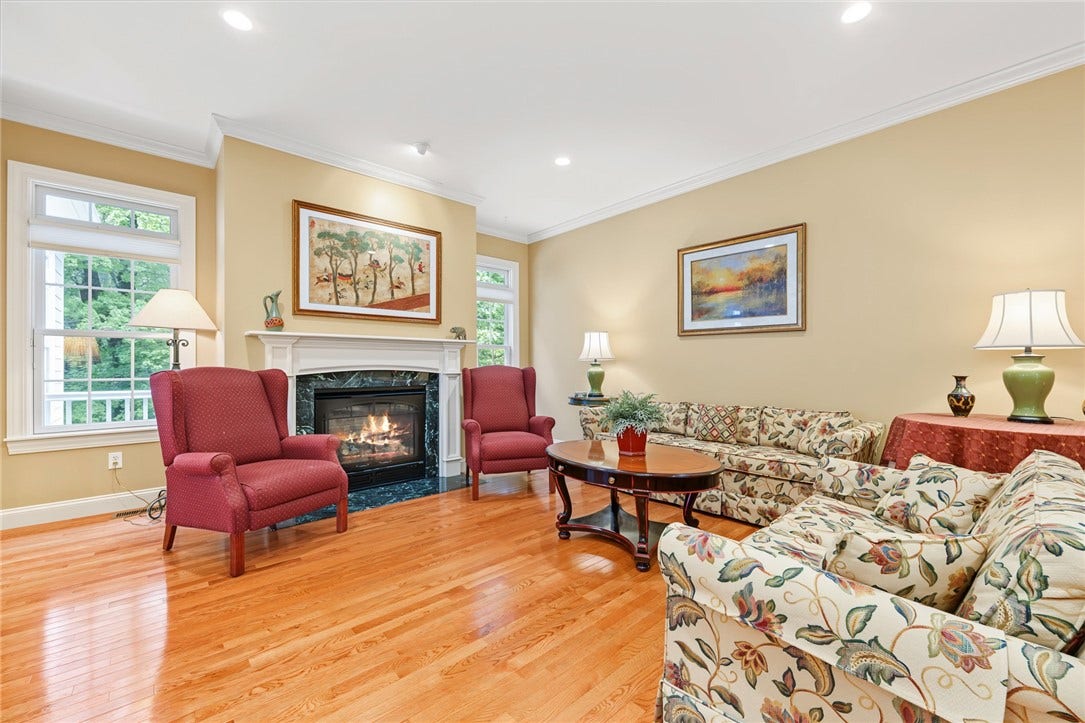 95 Fry Brook Drive, East Greenwich, RI 02818 Inviting living room featuring a classic fireplace with an elegant mantel and gleaming hardwood floors.