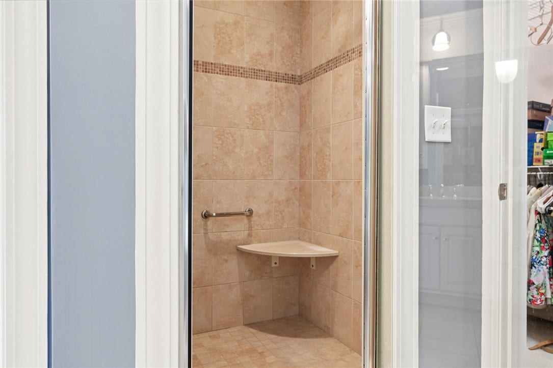 95 Fry Brook Drive, East Greenwich, RI 02818 A tiled walk-in shower features a glass enclosure, decorative mosaic detailing, and a built-in corner bench.