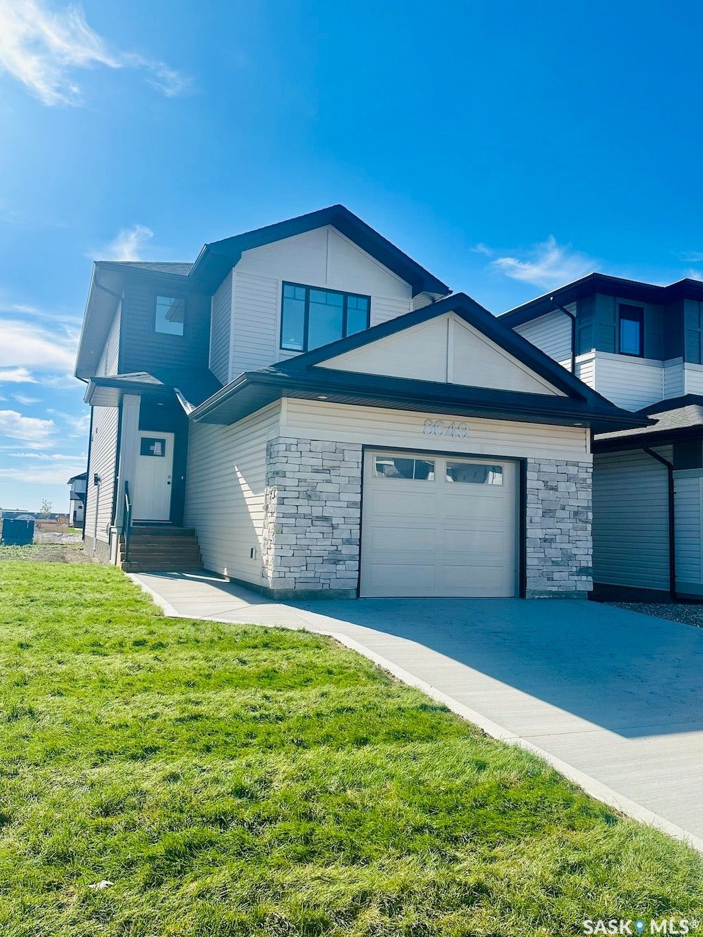 8649 Wheat Crescent, Regina SK S4Y 0H3 Modern architectural design featuring multi-toned siding, a prominent attached garage, and a concrete driveway