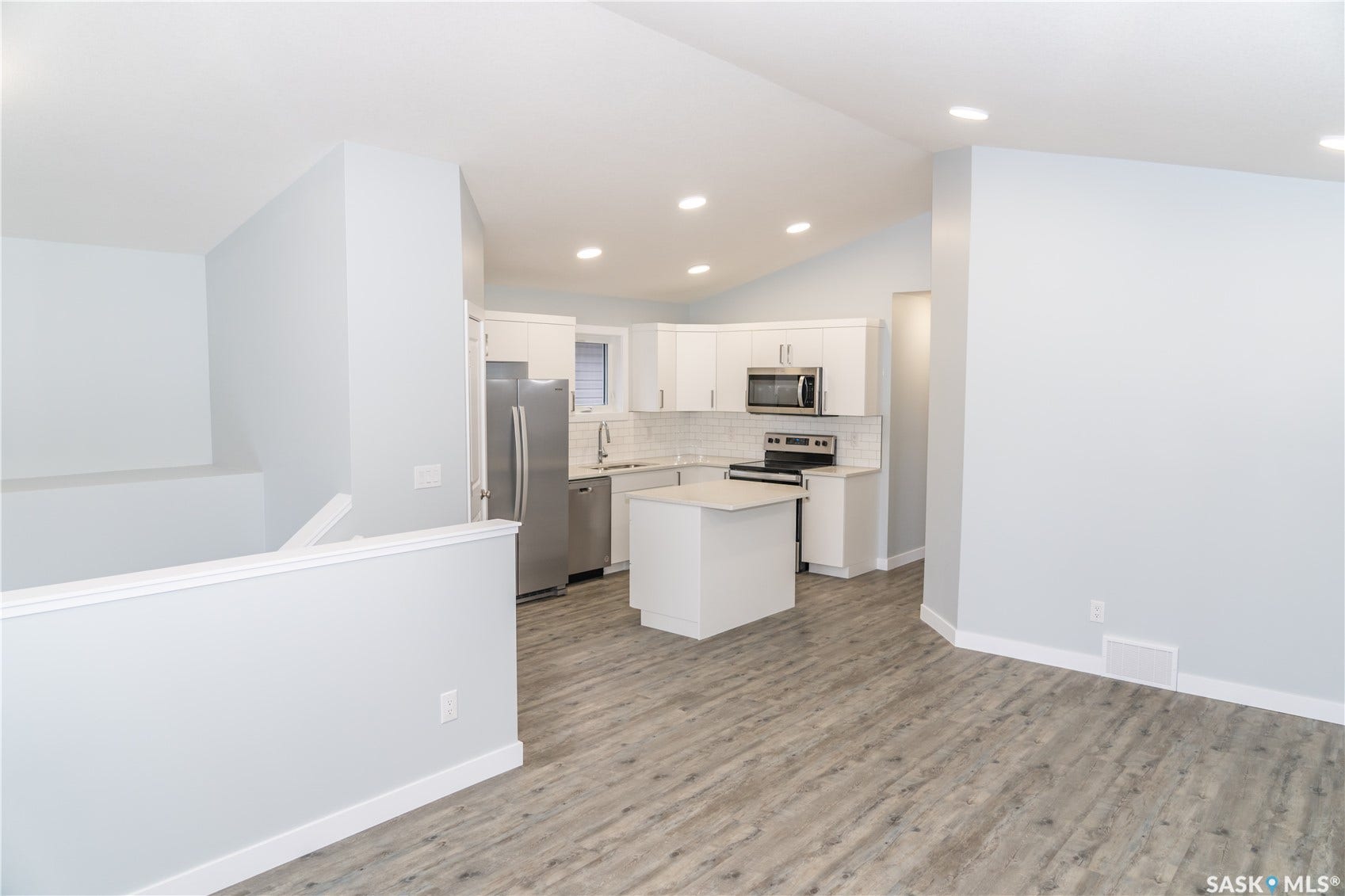 318 Stehwien Street, Saskatoon SK S7W 1H5 Kitchen with stainless steel appliances, white cabinets, a center island, and light hardwood / wood-style floors