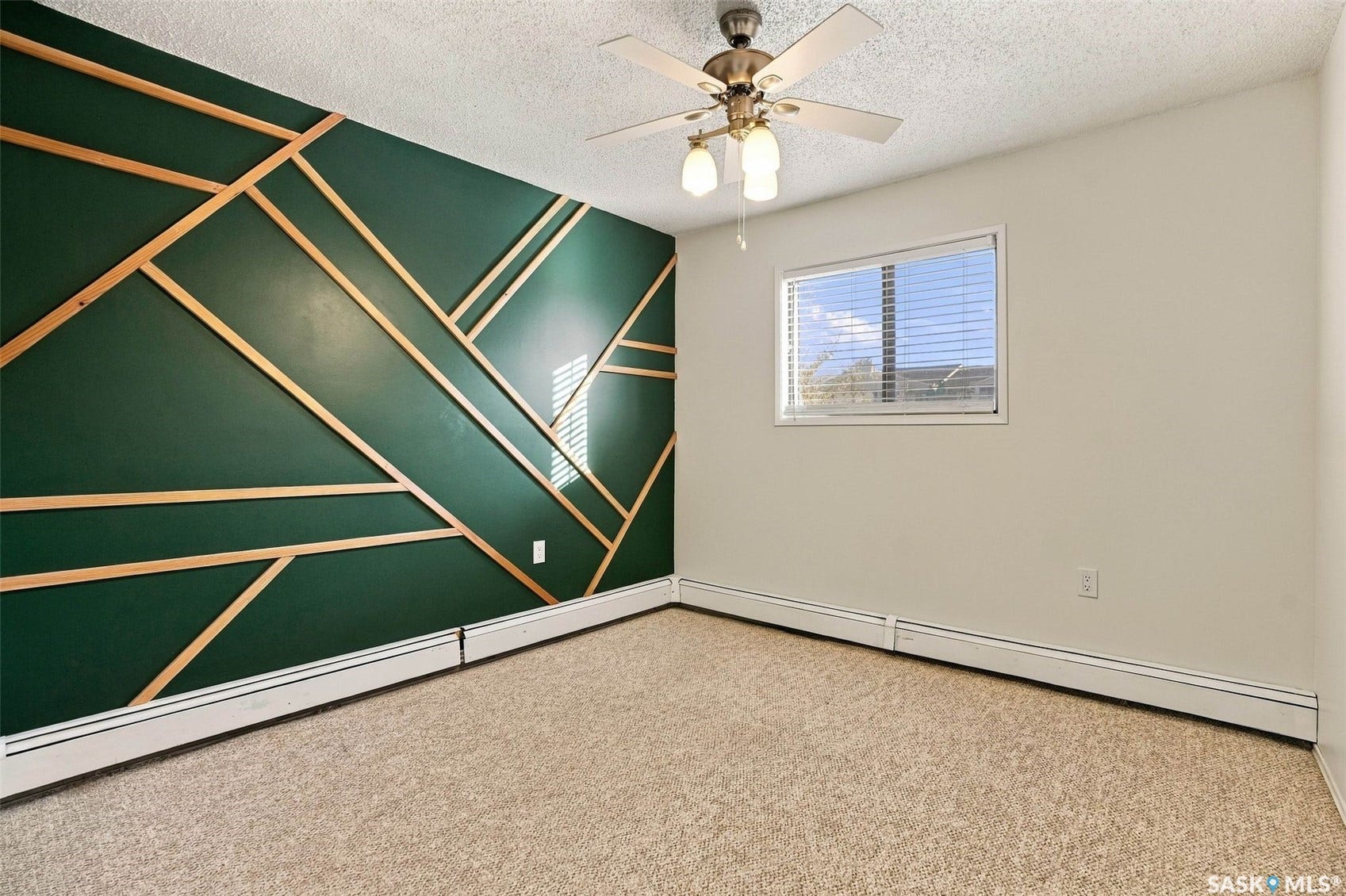 3410 Park Street, #119, Regina SK S4V 2M8 Feature wall with geometric wood paneling, textured ceiling, window with blinds, and ceiling fan with integrated lighting
