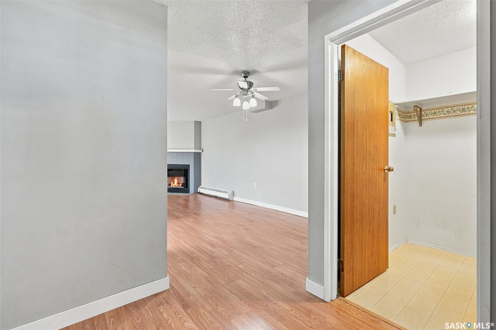 3410 Park Street, #119, Regina SK S4V 2M8 Open concept living space featuring wood-finish flooring, a fireplace with a mantel, and a ceiling fan