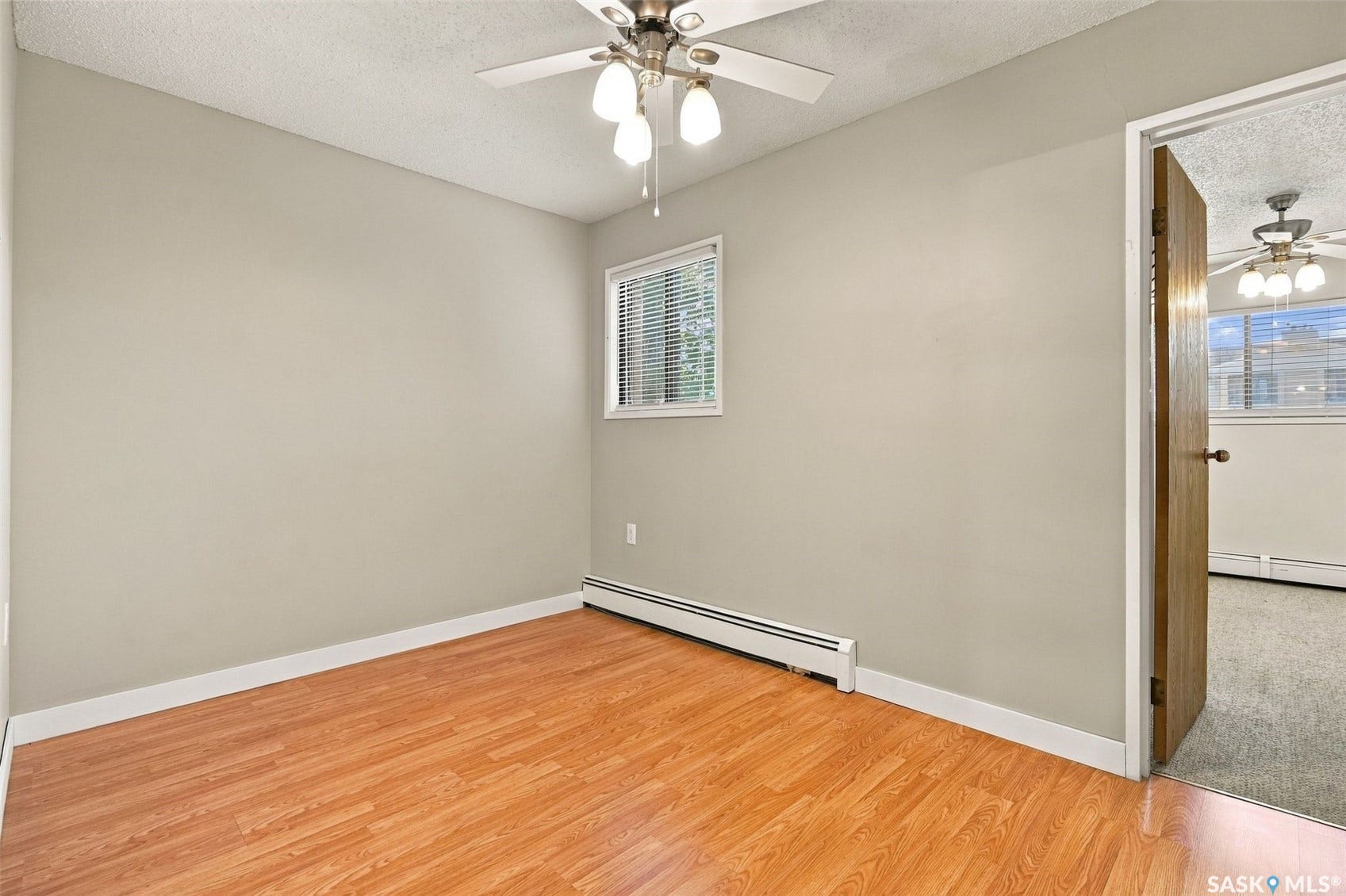 3410 Park Street, #119, Regina SK S4V 2M8 Hardwood-finish flooring, neutral wall tones, window with blinds, and ceiling fan with integrated lighting