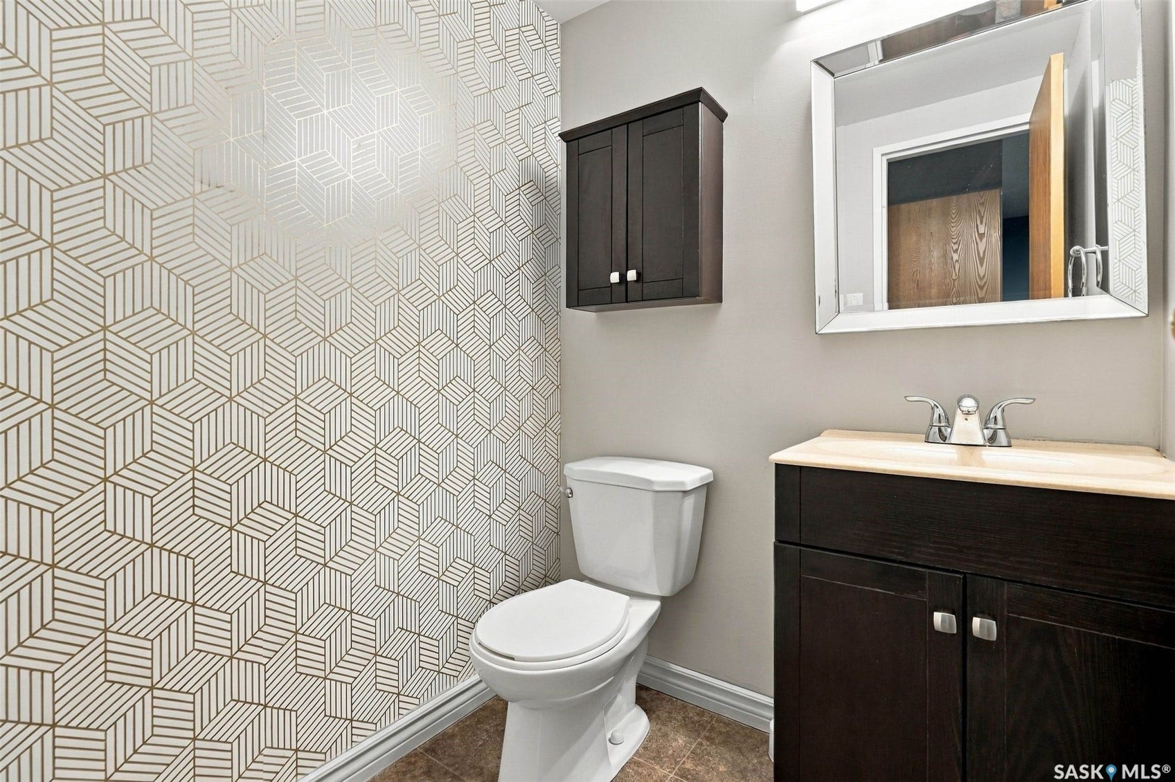 3410 Park Street, #119, Regina SK S4V 2M8 Geometric pattern accent wall, dark wood-finish vanity with light countertop, chrome faucet, wall-mounted storage cabinet, and rectangular mirror