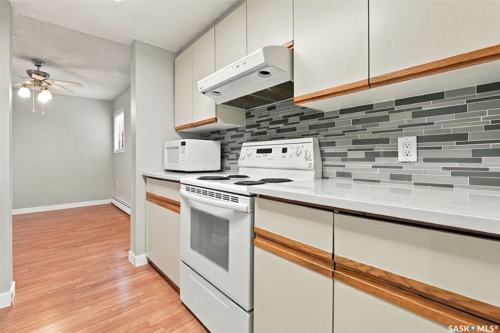 3410 Park Street, #119, Regina SK S4V 2M8 White kitchen cabinetry with wood-finish handles and white countertops