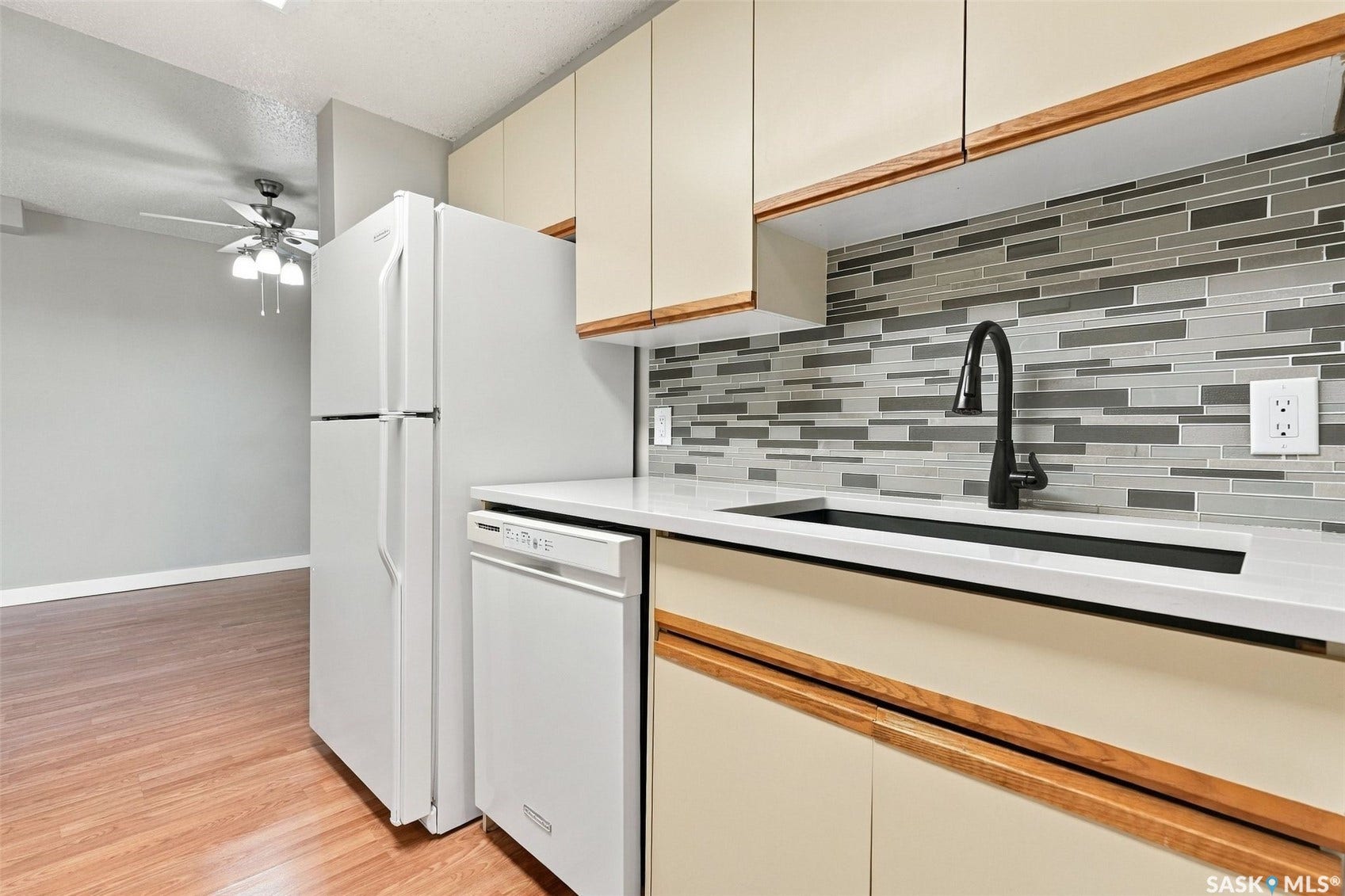 3410 Park Street, #119, Regina SK S4V 2M8 Kitchen featuring wood-finish flooring, white appliances, light cabinetry with wood accents, and a tile backsplash