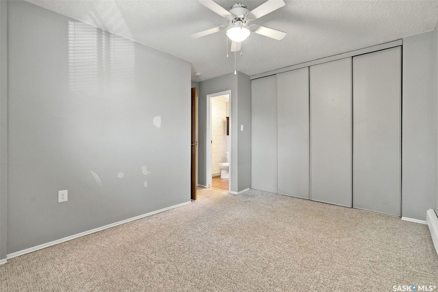 3410 Park Street, #119, Regina SK S4V 2M8 Carpeted room featuring a ceiling fan with integrated lighting, sliding closet doors, and light gray walls