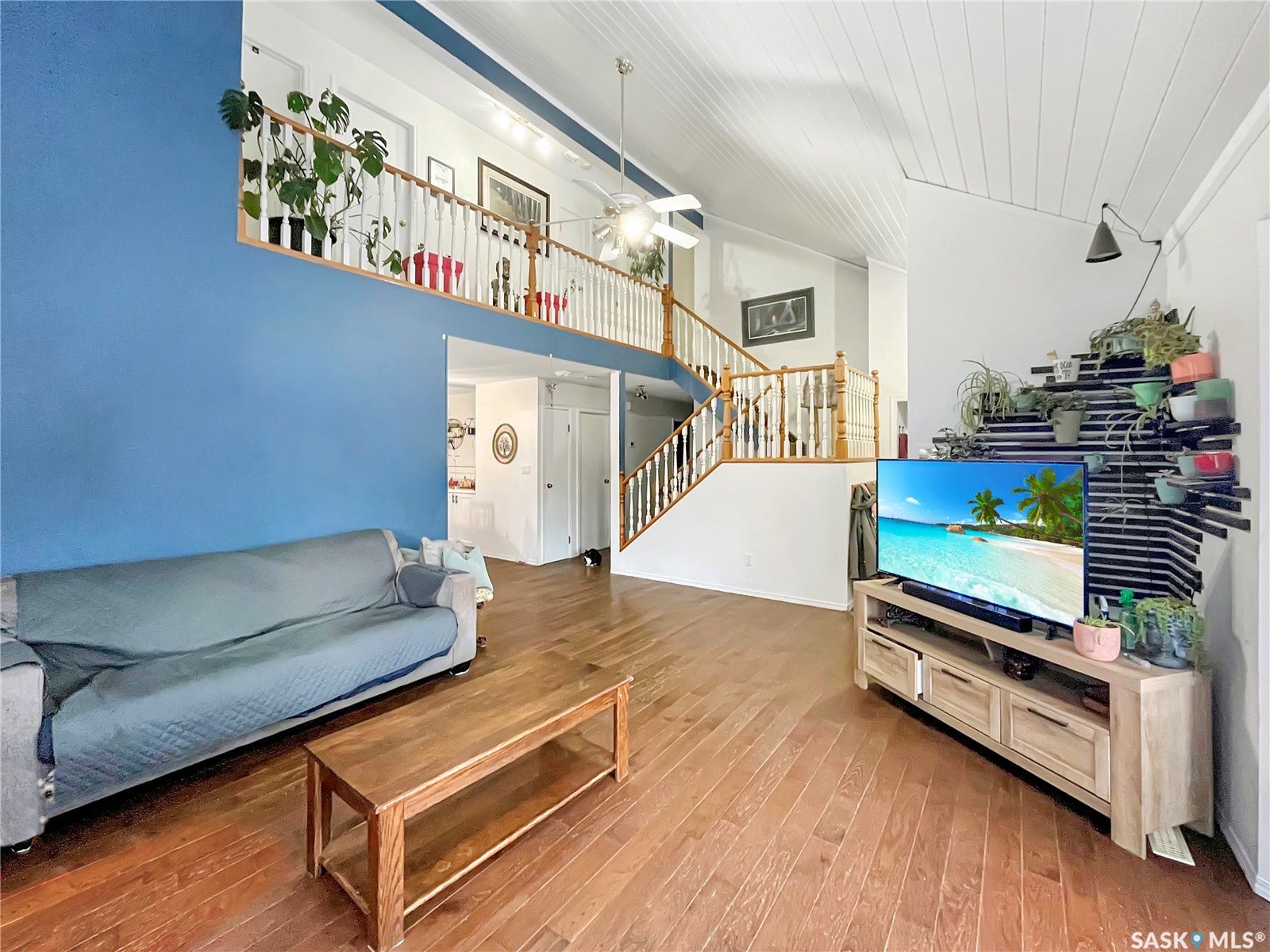 Vaulted ceiling with wood paneling, open-concept design, wood-finish flooring, and a second-story interior balcony