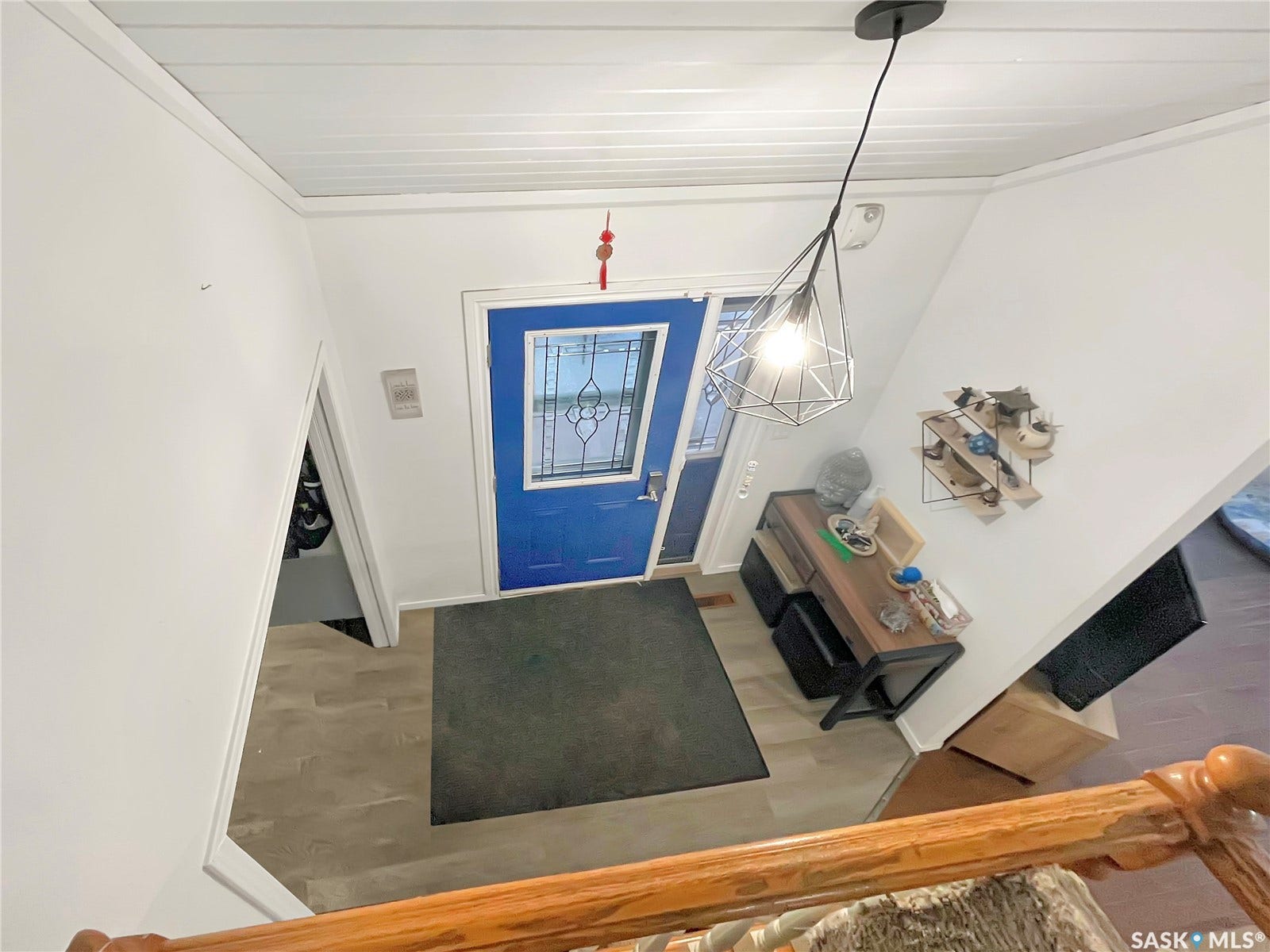Blue entry door with decorative glass inserts, wood-finish flooring, and white walls