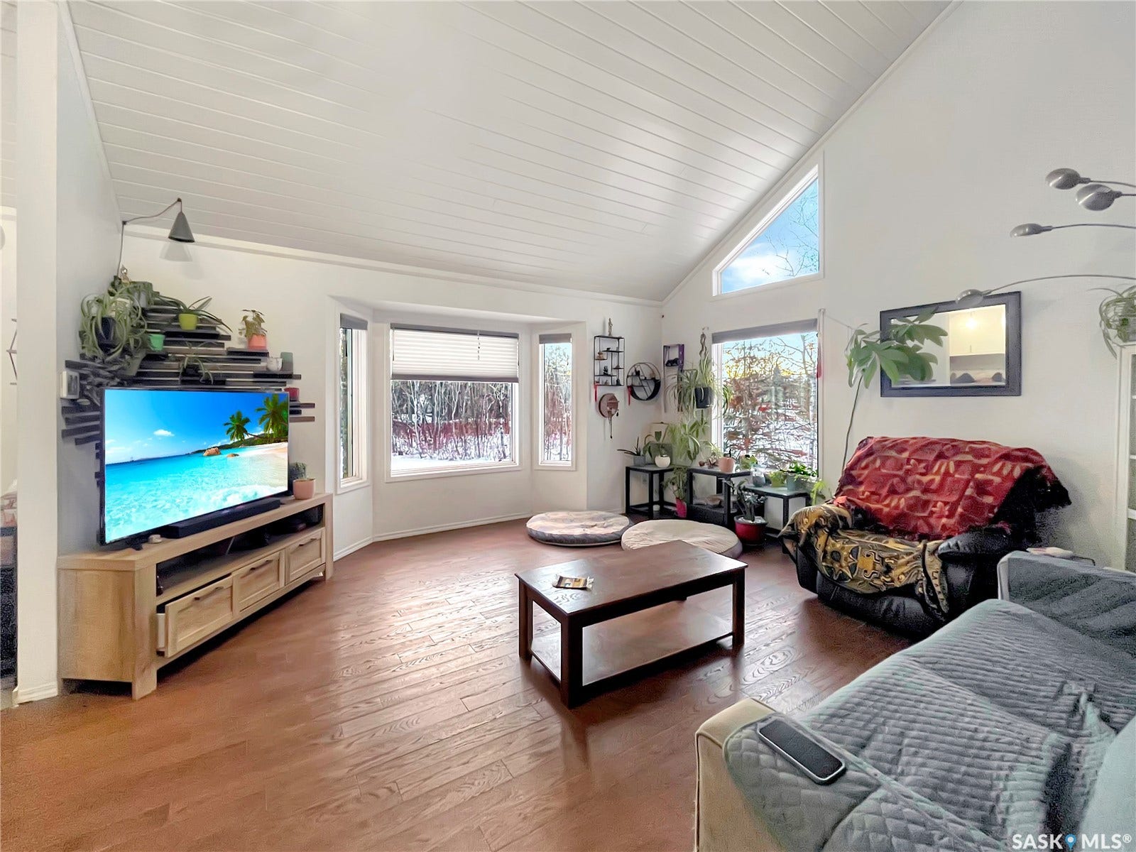 Vaulted ceiling with wood-finish paneling, wood-finish flooring, and a bay window