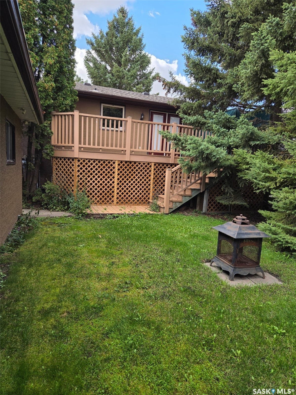 Multi-level wood deck with lattice skirting, double glass panel doors, and integrated steps