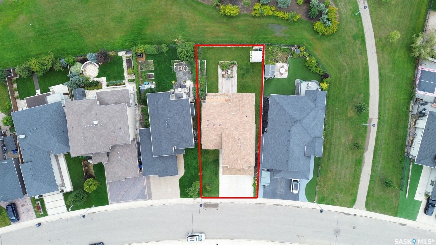 Expansive backyard featuring a manicured lawn, established landscaping, and a paved walking path
