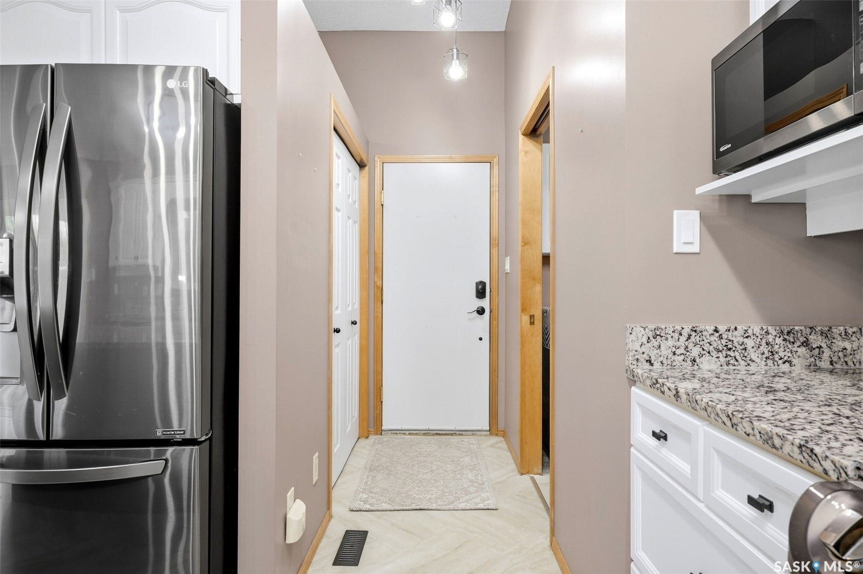 Stainless steel refrigerator, white cabinetry, speckled countertop, built-in microwave, and recessed lighting