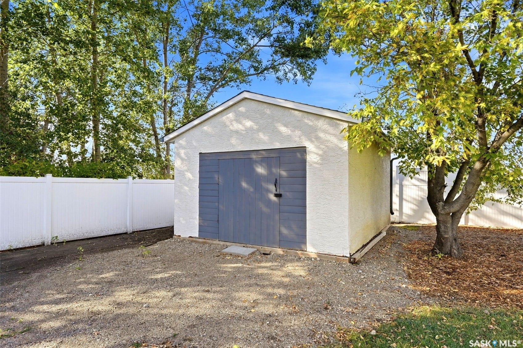 Detached garage with textured exterior, wooden doors, and gable roofline