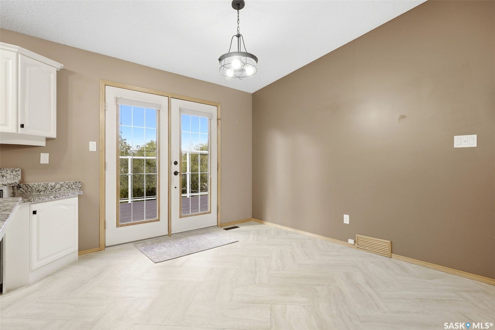 French doors, pendant lighting, white cabinetry, light-toned countertops, and light wood-finish flooring