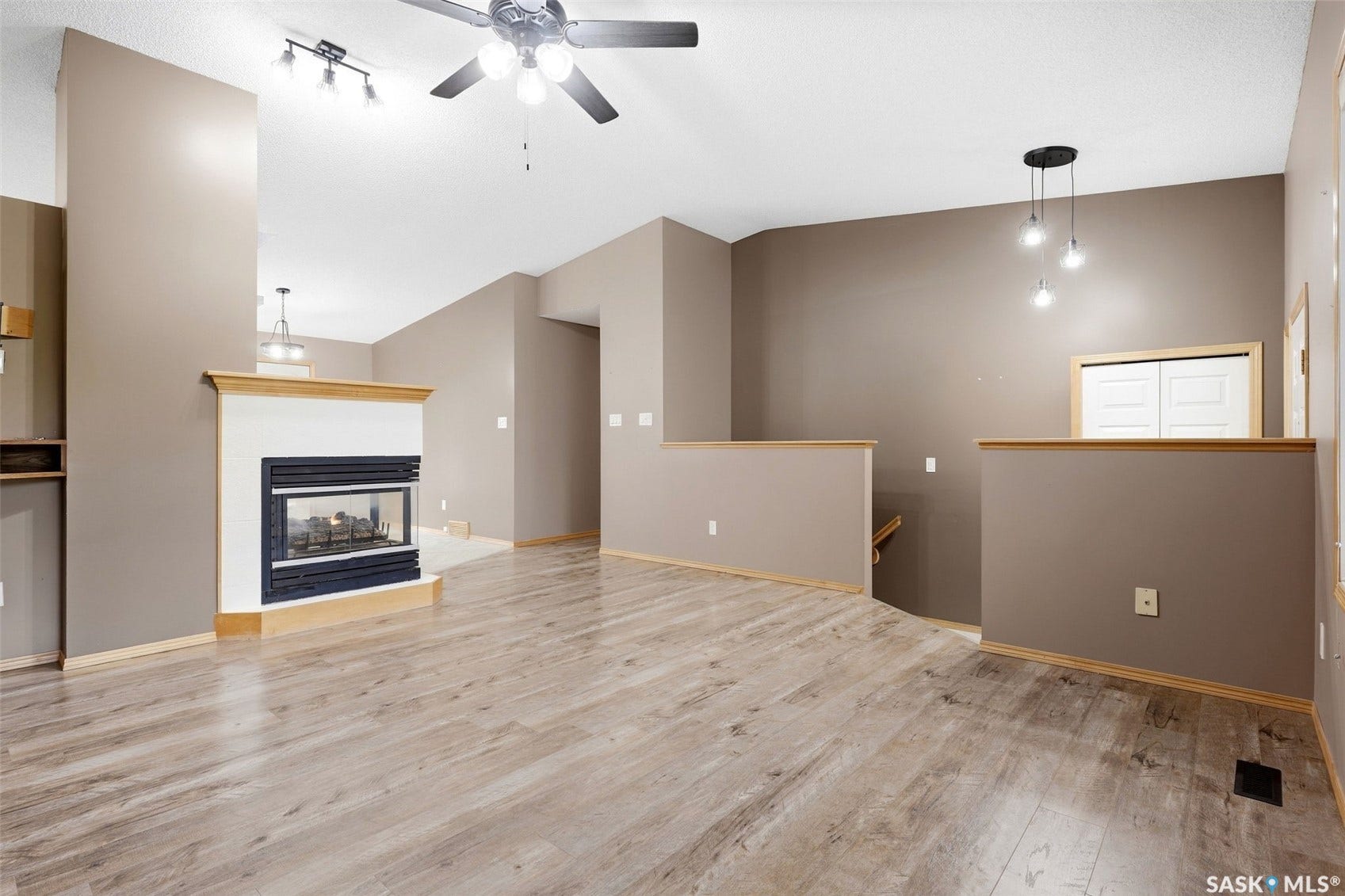 Wood-finish flooring throughout, a gas fireplace with mantel, ceiling fan with integrated lighting, recessed lighting, and a pendant light fixture