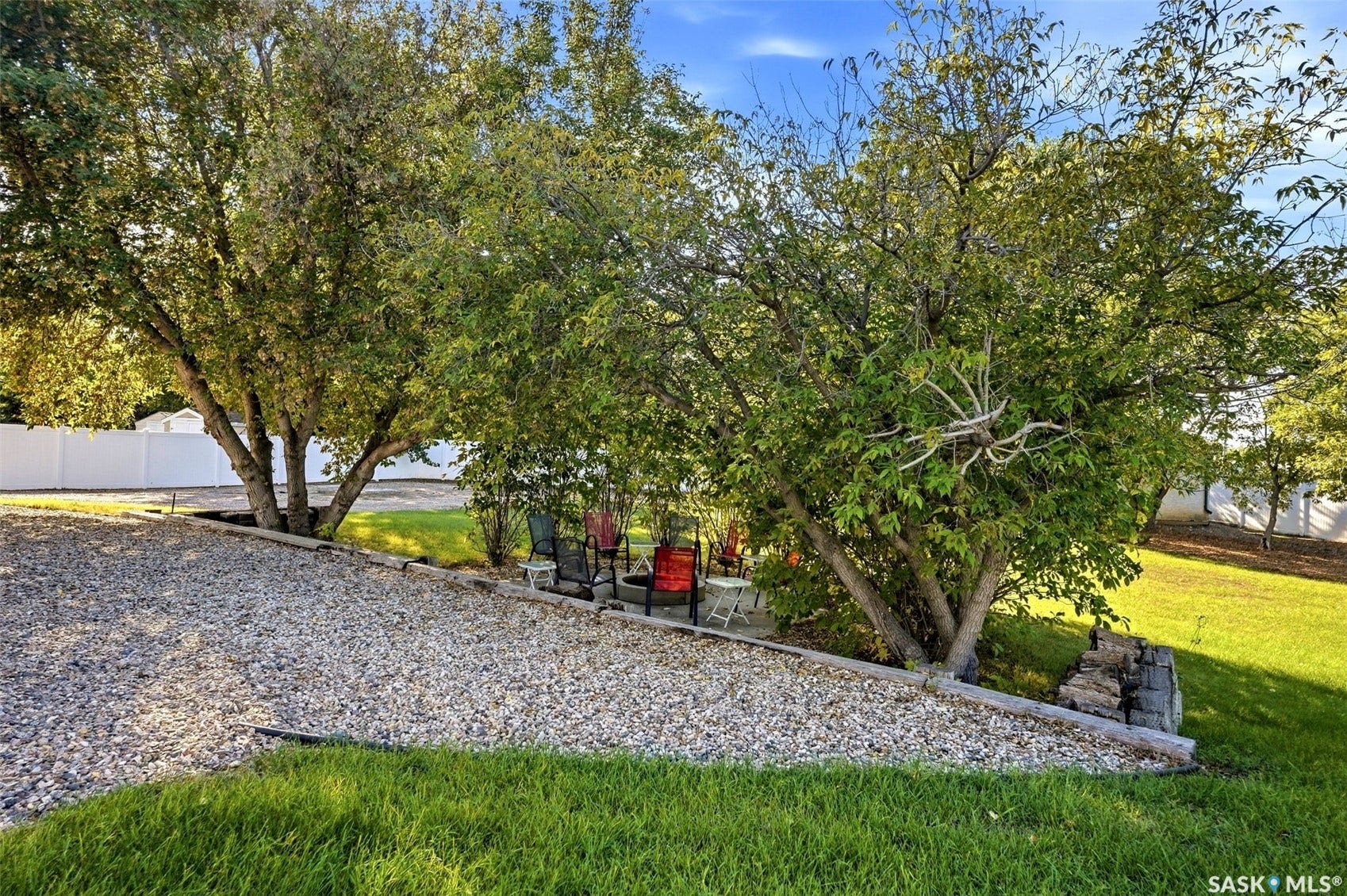 Gravel landscaping with a raised garden bed and mature trees